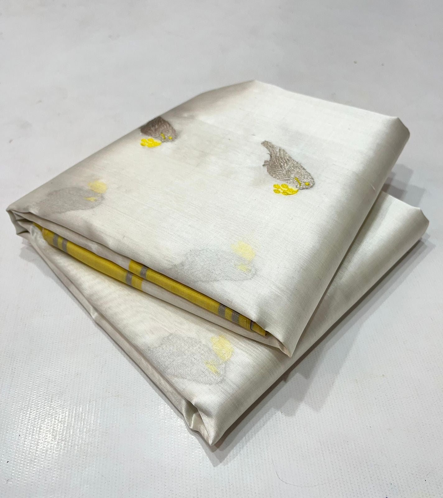 White Kerala Pattu Tissue Saree with Elephant Motifs and Yellow Border