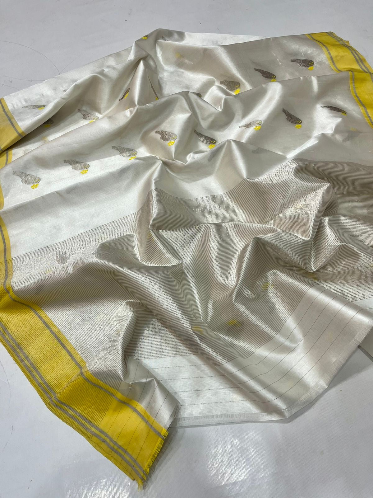 White Kerala Pattu Tissue Saree with Elephant Motifs and Yellow Border